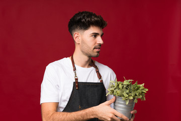 Young man over isolated background taking a flowerpot