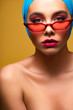 © LIGHTFIELD STUDIOS - sexy nude fashionable girl in trendy scarf and red sunglasses, isolated on yellow