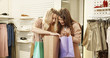 © VAKSMANV - Happy cheerful attractive young girls laughing after shopping in fancy clothes store. Beauiful Caucasian woman holding packets and looking inside them after buying new outfits. Female clients indoor.