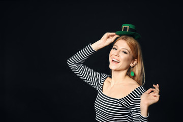 Wall Mural - Young woman with green leprechaun hat on black background, space for text. St. Patrick's Day celebration