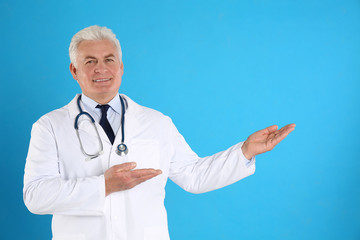 Canvas Print - Portrait of senior doctor against blue background