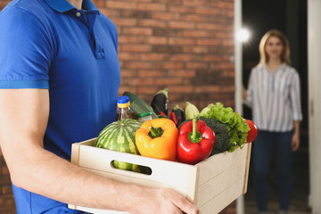 Courier with fresh products indoors, closeup. Food delivery service