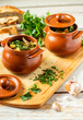 © Лаура Кенжегалиева - Clay pots with baked potatoes and chicken meat with pumpkin and choped greens on a wooden plank. Garlic and bread on the table