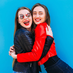 portrait of two pretty girls posing on the background of wall. H