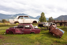 Old Rusty Car Bodies Of Russian Production. Car Cemetery In A Mountain Village