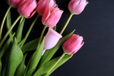 Fototapeta Tulipany - Menstrual cup and pink tulips on a black background. Menstruation, means of protection. Women's health, lifestyle.