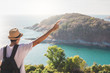 © OATZ TO GO FACTORY - Man wearing hat holds his hand happy. Man asian tourist Look at mountains and the sea Before sunset.for activity lifestyle outdoors freedom or travel tourism inspiration backpacker tourist to covid 19