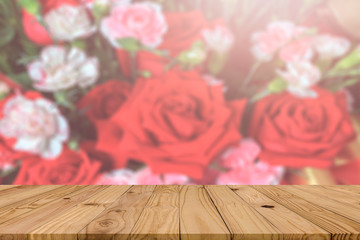 Wall Mural - Empty brown plank wooden board mock up display as shelf or desk with blurred group of red and pink roses in brightness lighting background.