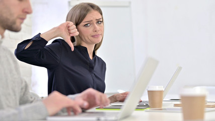  Disappointed Creative Woman showing Thumbs Down in Office