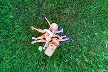 Family Have A Picnic With Pizza On A Green Grass, Aerial Top View