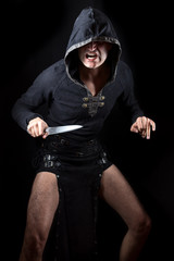 Young man posing in hooded gothic clothes with blade looking fierce