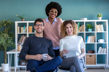 Wall Mural - Casual young business people looking at camera while working in the new office.