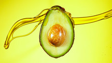 Fresh Cut Avocado With Oil Stream. Concept Of Healthy Fruit Also Useful In Cosmetics.