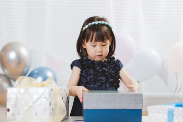 Wall Mural - toddler girl unpacking birthday gift box on her birthday party