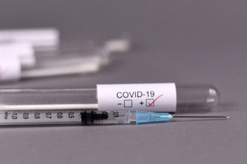 Wall Mural - syringe with medical test tube sample for coronavirus with label covid-19 in blurry background, conc