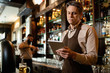 © Drazen - Smiling barista working on digital tablet in a pub.