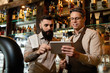© Drazen - Two bartenders using digital tablet while working in a bar.