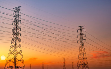 Silhouette high voltage electric pylon and electrical wire with purple and red sunset sky. Electricity poles at sunset. Power and energy concept. High voltage grid tower with wire cable. Steel pylons.