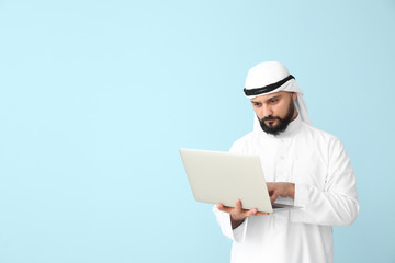 Canvas Print - Arab businessman with laptop on color background