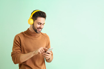 Poster - Handsome young man listening to music on color background