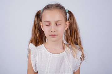 Portrait of a girl with a hairstyle two tails with closed eyes on a gray background