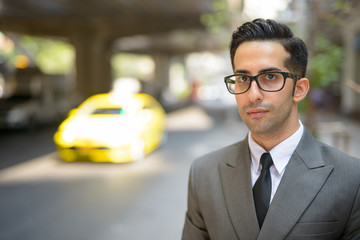 Wall Mural - Face of young handsome Persian businessman thinking in the city streets outdoors