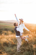 © sofiko14 - Shot of young boho hippie woman being carried by her handsome boyfriend in summer field. Couple having fun on their summer evening outdoors