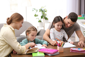 Canvas Print - Parents helping their daughters with homework at table indoors