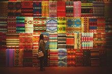 Side View Of Young Woman Standing Against Multi Colored Carpets On Display For Sale