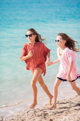 Little happy funny girls have a lot of fun at tropical beach playing together.