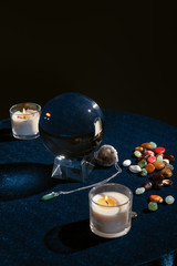 Wall Mural - Crystal ball with candles and occult objects on round table isolated on black