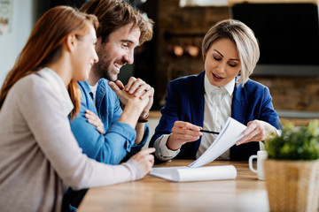 Happy couple and their insurance agent analyzing paperwork during a meeting.