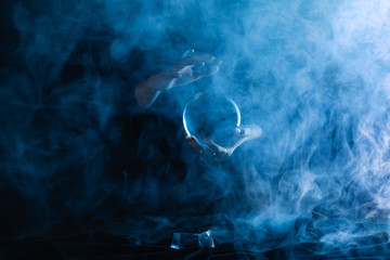 Wall Mural - Cropped view of witch holding crystal ball with smoke around on dark blue