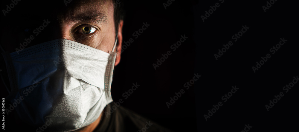 portrait of a man in a medical mask in a low key. a worldwide tragedy. COVID-19 virus pandemic warning - obrazy, fototapety, plakaty 