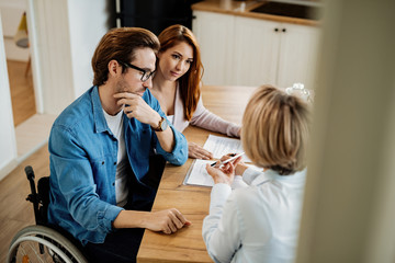 Wall Mural - Young couple and real estate agent using touchpad on a meeting at home.