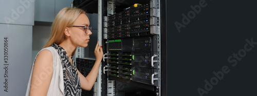 Young woman engineer It technician in the data center server room.