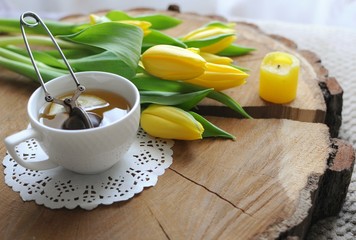 Enjoying green tea in the morning with yellow tulips on wooden table