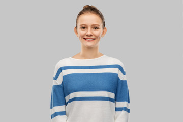 people concept - smiling teenage girl in pullover over grey background