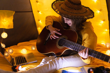 Wall Mural - little girl playing acoustic guitar under the tent in a living room.