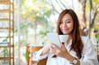 © Farknot Architect - Closeup image of a beautiful asian woman holding and using mobile phone while drinking coffee in cafe