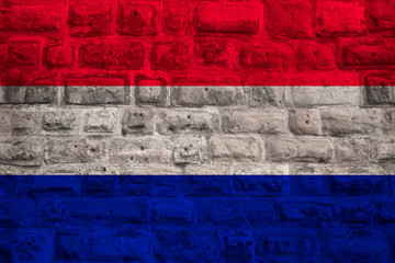 national flag of the modern state of the Netherlands on an old historical stone wall, concept of business, tourism, travel, emigration, globalization