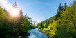 mountain river on a misty sunrise. fantastic nature scenery with fog rolling beneath a rainbow above the trees in fresh green foliage on the shore in the distance. beautiful countryside panorama