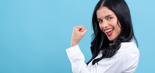 Wall Mural - Powerful young woman in a success pose on a blue background