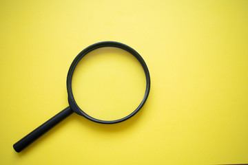 Wall Mural - Magnifying glass isolated on bright yellow background, bottom left corner