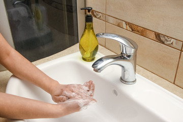 A Washing hands with soap under the faucet with water