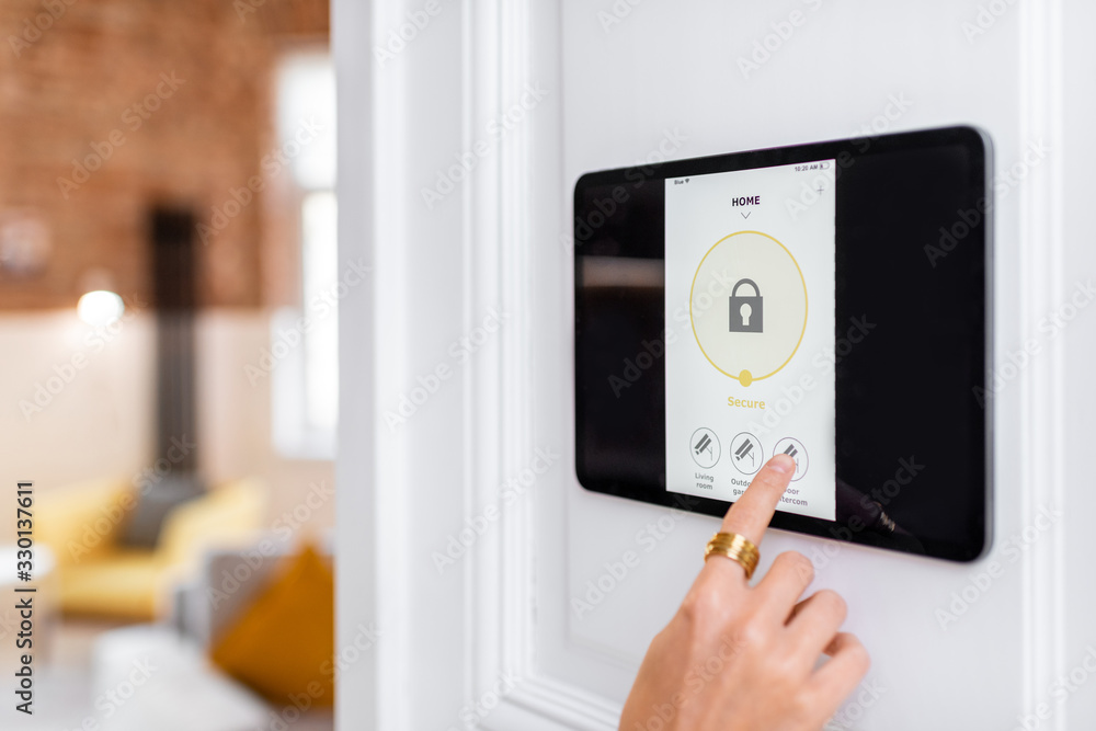 Controlling home alarm system with a digital touch screen panel installed on the wall. Concept of wireless secure control and smart home - obrazy, fototapety, plakaty 