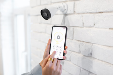 Controlling video surveillance and home alarm with mobile application, close-up on a smart phone with launched app. Concept of a wireless home security systems