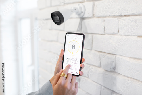 Controlling video surveillance and home alarm with mobile application, close-up on a smart phone with launched app. Concept of a wireless home security systems