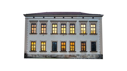 Low-rise 19th century european house isolated on white with warm lights in windows.