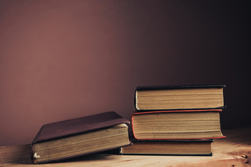 Poster - Vintage ancient books. Pattern background for design. The book on a brown wooden table table and red wall background.